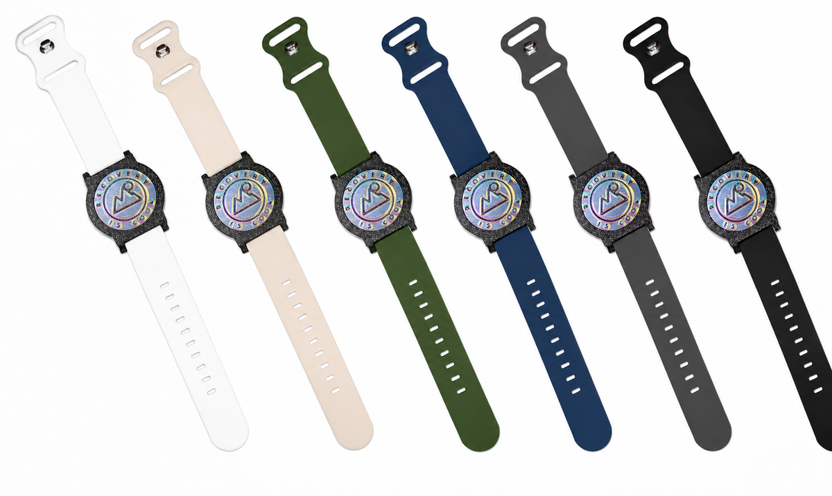 All six Recovewrist band colors laid flat — white, stone, olive green, navy, grey, and black silicone milestone bands, made in Colorado