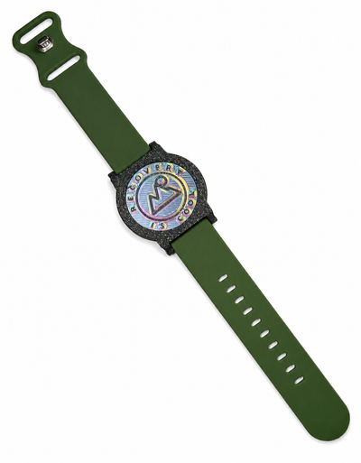 Recovewrist milestone band in olive green, worn watch-style with the iridescent ‘Recovery Is Cool’ recovery coin in a speckled granite bezel — made in Colorado